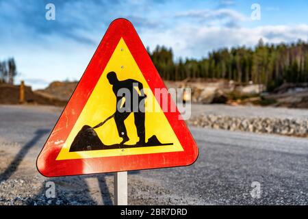 Nahaufnahme Foto von Dreieck gebildet rot orange reflektierende Warnung Verkehrsschild - Arbeitsbereich auf der Straße, sicher, langsame Fahrt. Verschwommener Hintergrund mit Straßenunrem Stockfoto