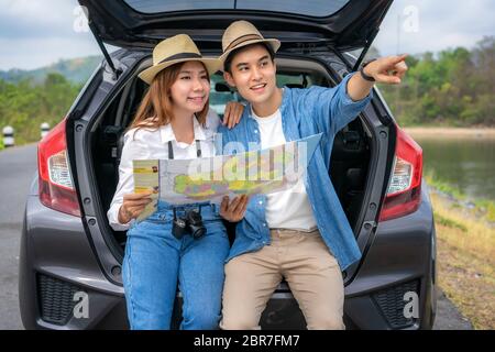 Porträt von asiatischen Paar im Auto sitzen mit Mann zeigt auf die Ansicht und Frau suchen schöne Landschaft und hält Karten während Urlaub zusammen in ho Stockfoto