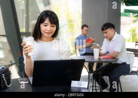 Asiatische junge Mann und Frau sitzen eine Person pro Tisch für Abstand von 6 Fuß Abstand schützen vor COVID-19 Viren für soziale Distanzierung für inf Stockfoto