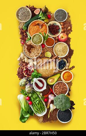 Große Auswahl an frischem Obst, Gemüse und Gewürze mit Impulsen, Granatapfel, Avocado, Artischocke, Samen, Endivie, Feigen- und Zitrone auf einem bunten Gelb Stockfoto