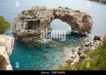 Es Pontas auf Mallorca mit Boot in der Nähe im Mittelmeer verankert. Mallorca Sonnenaufgang mit Yacht und Felsbogen bei Santanyi. Mallorca Cala Llombar Stockfoto