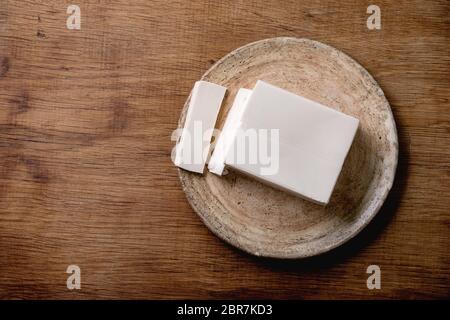 Seidentofu japanischer Sojakäse Vollstück auf Keramikplatte mit Essstäbchen über Holztisch. Flaches Layout, Platz Stockfoto