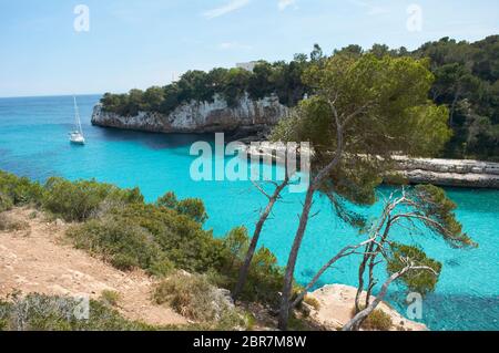 Es Pontas auf Mallorca mit Boot in der Nähe im Mittelmeer verankert. Mallorca Sonnenaufgang mit Yacht und Felsbogen bei Santanyi. Mallorca Cala Llombar Stockfoto