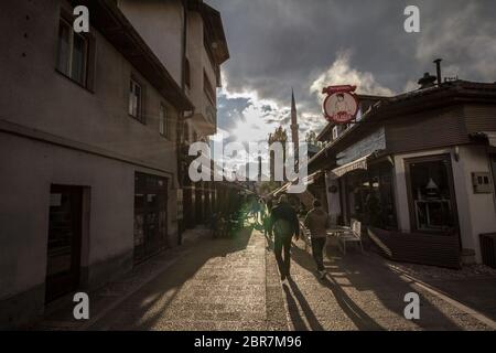 SARAJEVO, BOSNIEN UND HERZEGOWINA - 17. APRIL 2017: Straße mit Touristen und einem Moschee-Minarett im Stadtteil Bascarsija. Bascarsija ist ein Symbol von Sa Stockfoto