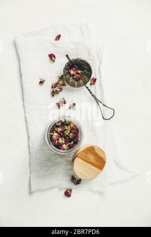 Tee mit trockenen Rosenblüten im Glas und Teesieb. Draufsicht, flaches Lay Stockfoto