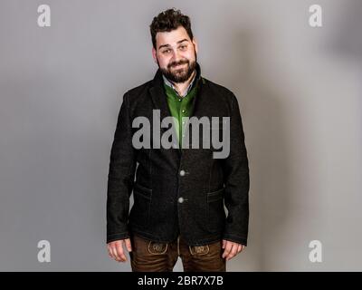 Cool Mann mit Tracht posiert vor grauem Hintergrund Stockfoto