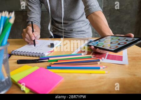 Männer arbeiten als Fashion Designer beschließen, auf die Farbkarte für Kleidung in der digitalen Tablet am Arbeitsplatz studio Stockfoto