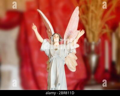Eine weibliche Jugendstil Engel in einer Kapelle, mit den Armen und hob die Hand hoch, große umgedrehter Flügel, kleine Porzellan Figur. Der Hintergrund in dunklem Rot, v Stockfoto