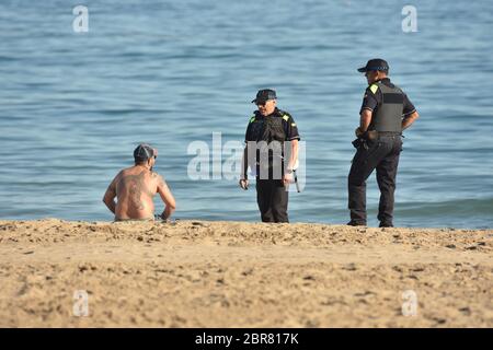 Calafell, Tarragona, Spanien. Mai 2020. Zwei lokale Calafell Polizisten sprechen mit einem Mann am Strand, während sie während der Endkonkavierung von Phase 1 patrouillieren.Calafell befindet sich in Phase 1 des Endes der Haft, aber mit strengen Maßnahmen, wo Sie auf den Terrassen der Restaurants mit den Sicherheitsmaßnahmen von sein können 2 Meter zwischen den Tischen, gehen Sie am Strand, aber nicht auf dem Sand sitzen gestreckt oder baden. Die örtliche Polizei führt Straßenkontrollen durch, um die Einhaltung der Vorschriften zu kontrollieren. Quelle: Ramon Costa/SOPA Images/ZUMA Wire/Alamy Live News Stockfoto