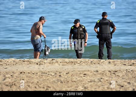 Calafell, Tarragona, Spanien. Mai 2020. Zwei lokale Calafell Polizisten sprechen mit einem Mann am Strand, während sie während der Endkonkavierung von Phase 1 patrouillieren.Calafell befindet sich in Phase 1 des Endes der Haft, aber mit strengen Maßnahmen, wo Sie auf den Terrassen der Restaurants mit den Sicherheitsmaßnahmen von sein können 2 Meter zwischen den Tischen, gehen Sie am Strand, aber nicht auf dem Sand sitzen gestreckt oder baden. Die örtliche Polizei führt Straßenkontrollen durch, um die Einhaltung der Vorschriften zu kontrollieren. Quelle: Ramon Costa/SOPA Images/ZUMA Wire/Alamy Live News Stockfoto