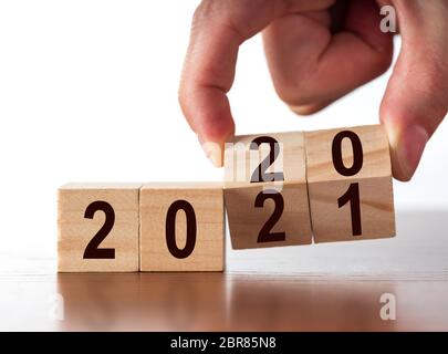 Neujahrskonzept von 2020 bis 2021. Handwechsel Holzwürfel auf weißem Tisch. Stockfoto