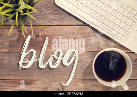 Blog Text mit Computer Tastatur, Tasse Kaffee und dem Blumentopf. Holztisch Hintergrund in Vintage getönt. Stockfoto