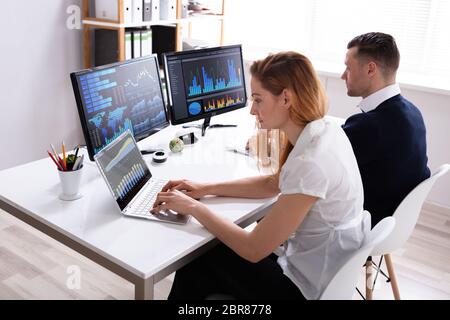 Männliche und weibliche Börse Broker Analyse Diagramme auf dem Computer im Büro Stockfoto