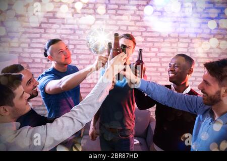 Hohe Betrachtungswinkel der Multirassischen Freunde zusammenpressen Bierflaschen Disco Bar Stockfoto