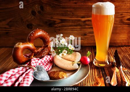 Bayerische Spezialitäten frisches Bier mit Salzbrezel und Weißwurst auf rustikalem Holz zum Oktoberfest Stockfoto