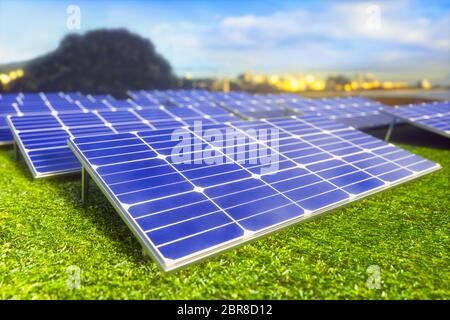 Solar Panels, die sich über das Feld, auf das grüne Gras. Im Hintergrund die Stadt, für die Energie vorhanden ist. Stockfoto