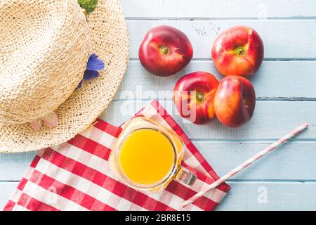 Reife flache Nektarinen und Saft auf blauem Tisch. Draufsicht. Stockfoto