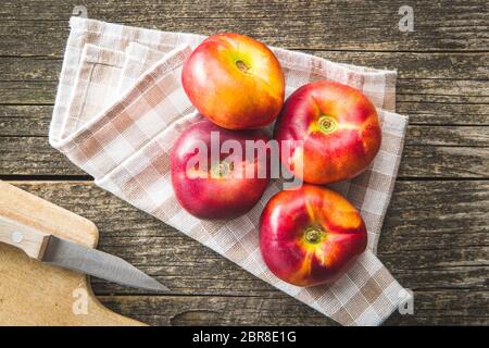 Reife flache Nektarinen auf karierter Serviette. Draufsicht. Stockfoto