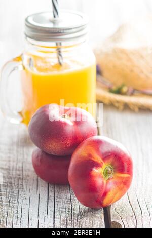 Reife flache Nektarinen und Saft auf altem Holztisch. Stockfoto