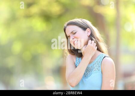 Frau mit Juckreiz kratzen Hals stehen draußen in einem Park Stockfoto