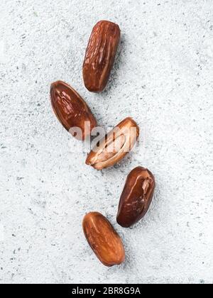 Süße raw Termine auf grauzement Hintergrund. Ganze Termine und Hälfte mit Knochen Datum auf grauem Beton Oberfläche. Zucker freie Alternativen konzept mit Platz fo Stockfoto