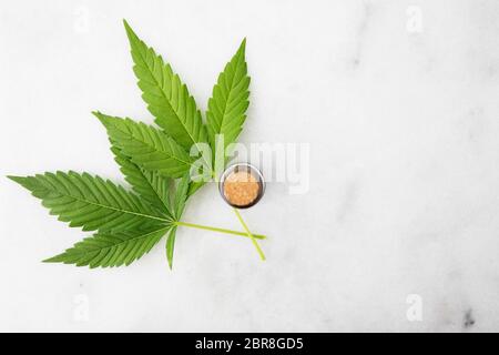 Cannabis leaf mit Flasche CBD Öl auf Marmor Oberfläche mit Kopie Raum aus gesehen direkt über Stockfoto