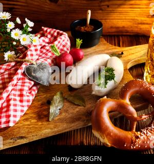 Rustikale bayerische Weißwurst mit Brezel auf Holzschneidebrett für ein oktoberfest Stockfoto