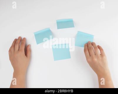 Menge blau Aufkleber auf einem weißen Hintergrund und zwei weibliche Hände auf Ihn gerichtet, konzeptionellen Hintergrund Stockfoto