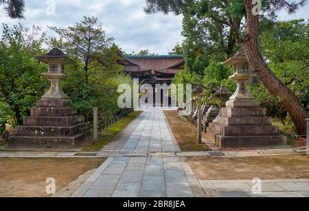 Der Blick auf die traditionellen kaku-doro (quadratische) Steinlaternen stangten entlang des Passes am Kitano Tenmangu Schrein. Kyoto. Japan Stockfoto