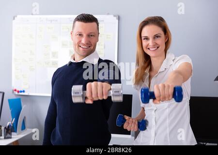 Nahaufnahme der männlichen und weiblichen Unternehmer Trainieren in Office mit Hanteln Stockfoto