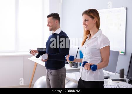 Nahaufnahme der männlichen und weiblichen Unternehmer Trainieren in Office mit Hanteln Stockfoto