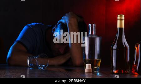 Flaschen mit alkoholischen Getränken und die Abbildung von einem betrunkenen Mann Stockfoto