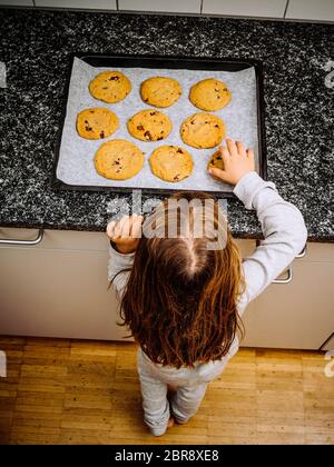 Foto eines jungen Mädchens zu einem Fach des warmen Chocolate Chip Cookies starrte. Stockfoto