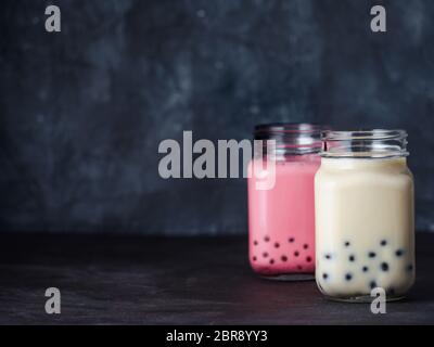 Hausgemachte Milch Bubble Tea mit Tapioka Perlen Kugeln. Beliebte Taiwan Bubble Tea in Glas Marmeladenglas mit Kopie Platz für Text. Zwei Bubble Tea auf dunklen zurück Stockfoto