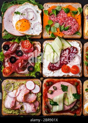 Satz von acht verschiedenen Sandwiches mit Fleisch in quadratische Form. Top View oder flach. Sortiment Fleisch Toast auf schwarzem Hintergrund. Idee, kreative Konzept Stockfoto