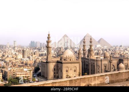 Blick auf den Mosque-Madrassa der Sultan Hassan in Kairo und die Pyramiden von Gizeh, Ägypten. Stockfoto