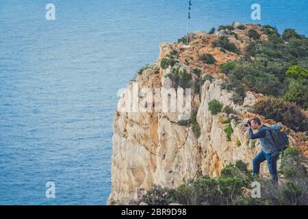 Touristische stehen am Rand einer Klippe und Fotografieren der atemberaubenden Klippen in Schiffswrack Bucht im Sommer auf Zakynthos Insel, Griechenland Stockfoto