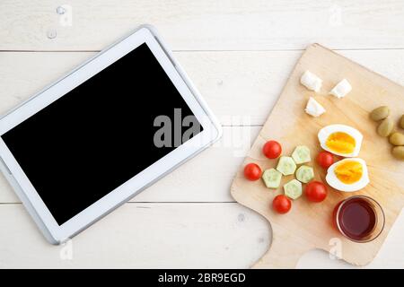 Tablet, Tee und türkischen, mediterranen Frühstück vor dem Beginn des Arbeitstages oder während der Arbeit auf einem hellen Holz- Fach auf einem weissen natürlichen backgrou Stockfoto