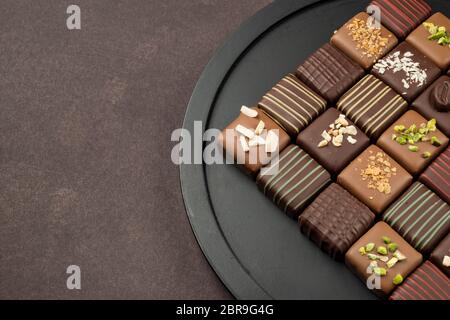 Pralinen Vielfalt in schwarz Fach auf braunem Hintergrund Stockfoto