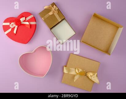 Verschiedene leere offene Papier Geschenkboxen auf lila Hintergrund, Ansicht von oben, festliche Kulisse Stockfoto