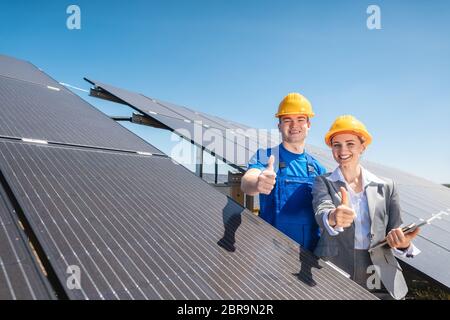 Arbeiter und Investor in Solarkraftwerk zeigt auf die Sonne Stockfoto