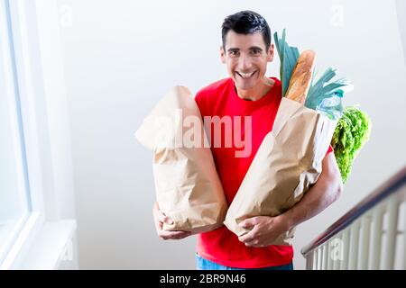Lebensmittelgeschäft Lieferung Mann trägt rote Polo-Shirt liefert Lebensmittel Stockfoto