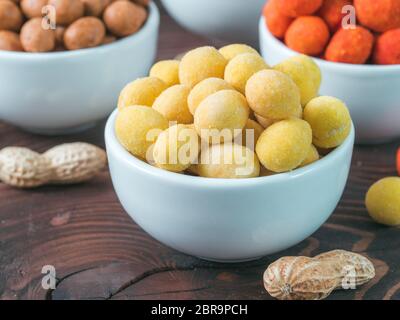 Peanut Snack für Bier, Wein, Party Bar. Gesalzene Erdnüsse in gelben Käse Glasur auf braune Holztisch. Kopieren Sie Platz. Stockfoto