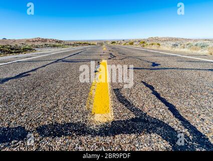 Blick auf eine endlose gerade Straße durch die Wüste in den USA läuft Stockfoto