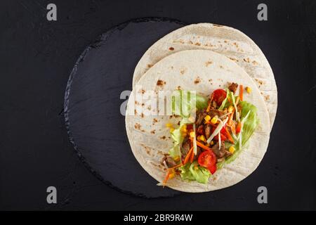 Burritos Wraps mit Hähnchen und Gemüse auf schwarzem Schiefer. Chicken burrito, mexikanisches Essen. Stockfoto
