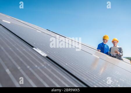 Arbeiter und Investor in Solarkraftwerk zeigt auf die Sonne Stockfoto