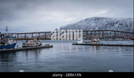 Tromsø, Norwegen - Dezember 2018: Hafen und Hafen mit dem berühmten tromso Brücke über Tromsoysundet Straße im Hintergrund Stockfoto