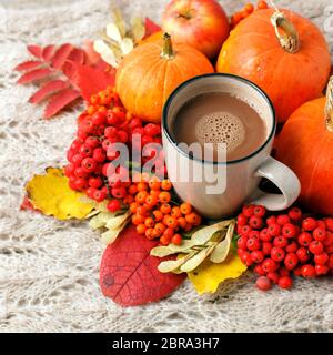 Gemütliche Herbstkomposition. Heißer Kakao in Keramik-Becher umgeben von Herbstblättern und Kürbissen auf warmem Karomee. Grußkarte, Café-Bar, Thanksgiving hal Stockfoto