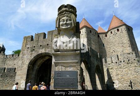 Eine geschlossene Ansicht der Statue der Sarazenen Prinzessin aka Lady Carcas mit Tor der Narbonne Zitadelle von Carcassonne im Hintergrund.Aude, Occitanie.Frankreich Stockfoto