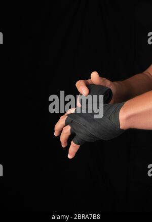 Man wickelt seine Hände in Schwarz textile Bandage für Sport, schwarzer Hintergrund, Kopie Raum Stockfoto